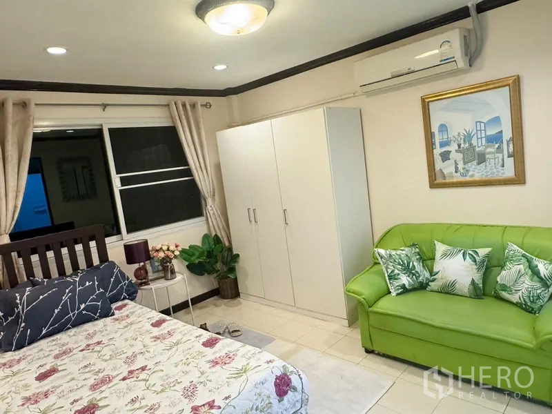 联排别墅 出租在Prawet, Bangkok - 客卧配绿色小沙发、白色衣柜与窗帘。