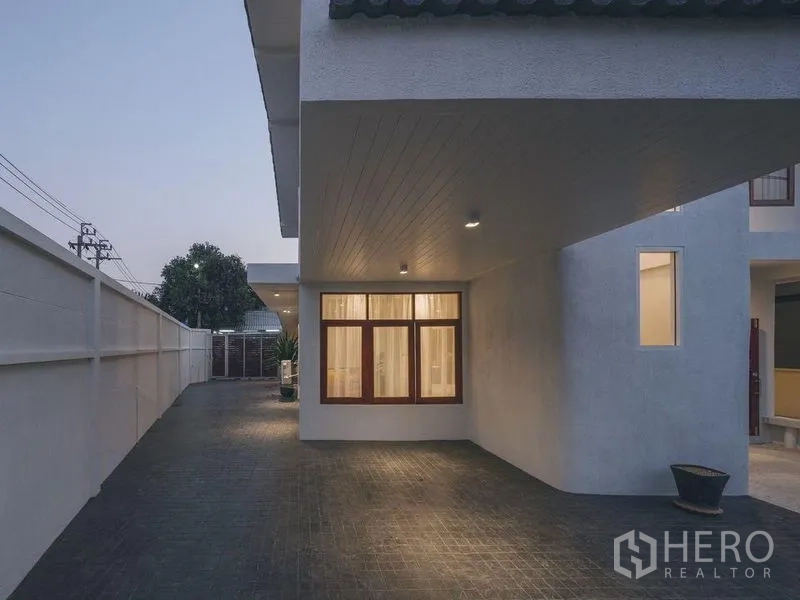 Detached House for sale in Chatuchak, Bangkok - Covered carport and long paved driveway with exterior wall lights.