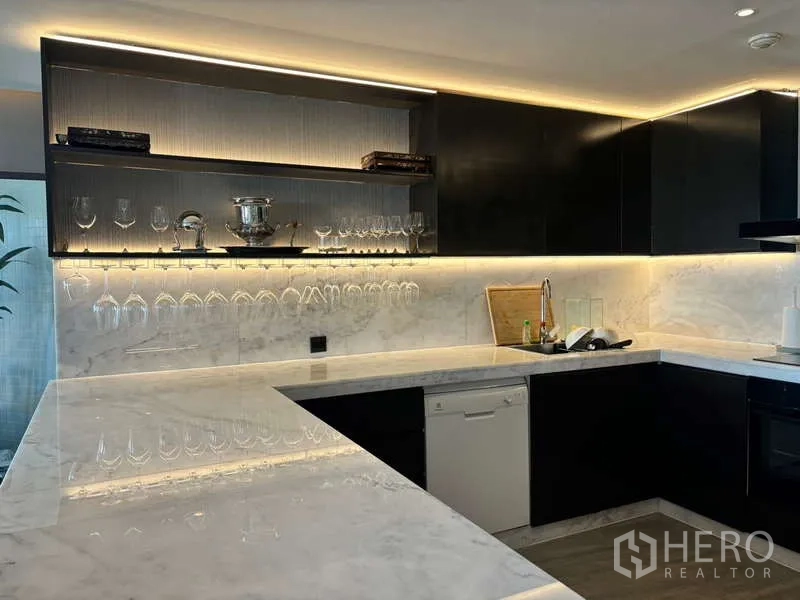 Condominium for rent in Watthana, Bangkok - Gourmet kitchen with marble countertops, black cabinets and under-cabinet lights.
