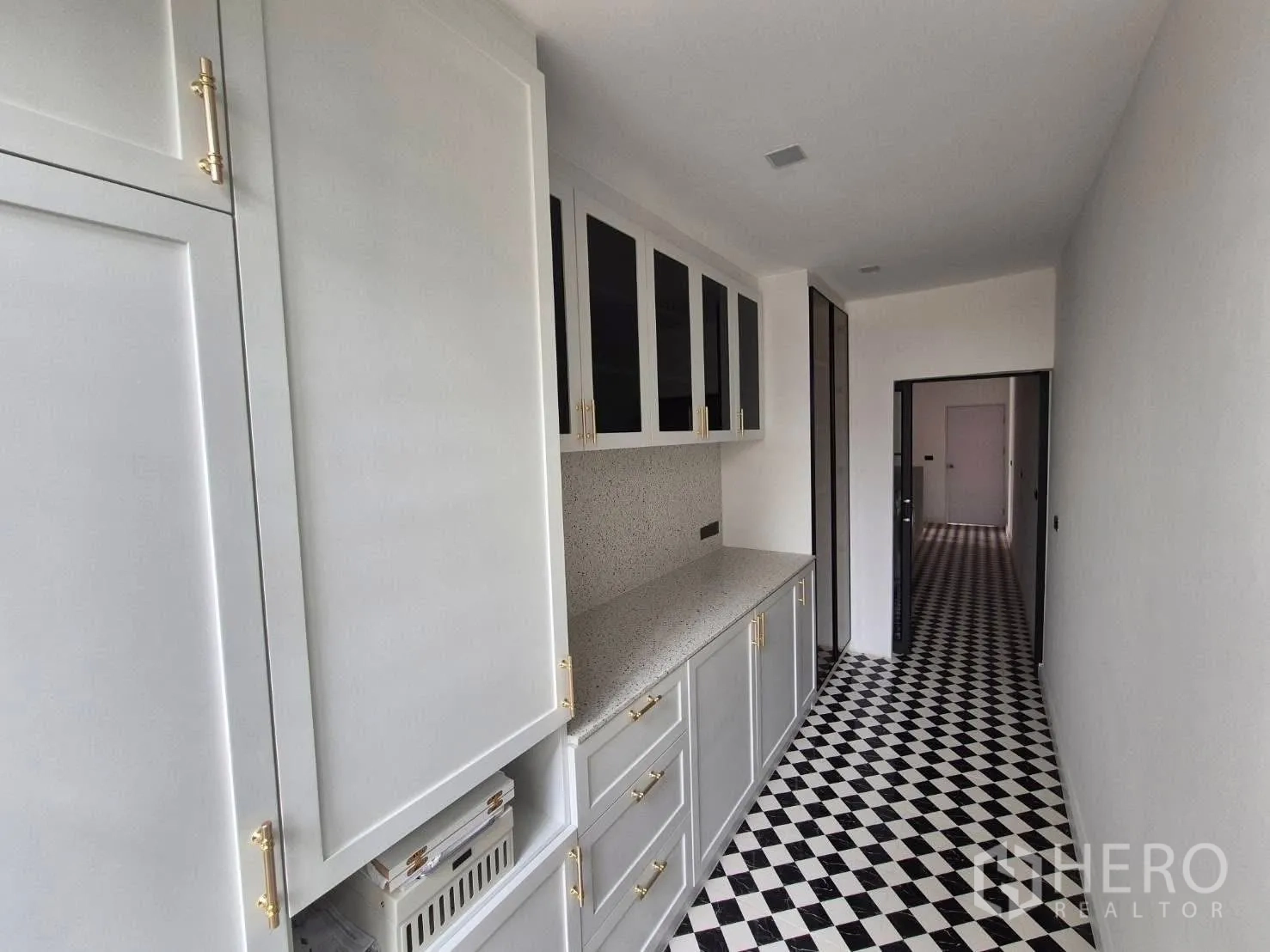 Detached House for sale in Bang Kruai, Nonthaburi - Pantry corridor with light cabinetry, stone countertop and black‑white tiled floor.