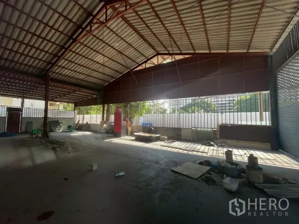 Warehouse for rent or sale in Yan Nawa, Bangkok - Open warehouse interior with steel truss roof and wide loading opening allowing natural light.