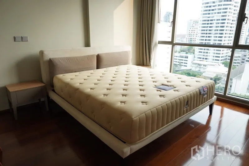 Condominium for rent in Watthana, Bangkok - Sunlit bedroom with king bed and floor-to-ceiling windows overlooking the Bangkok skyline.