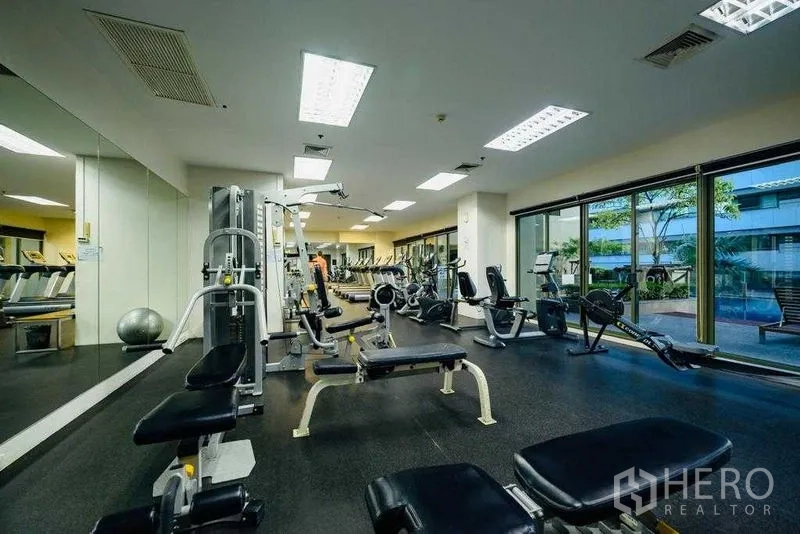 Condominium for rent in Watthana, Bangkok - Fully equipped fitness center with weight machines, cardio equipment, and wall mirrors.