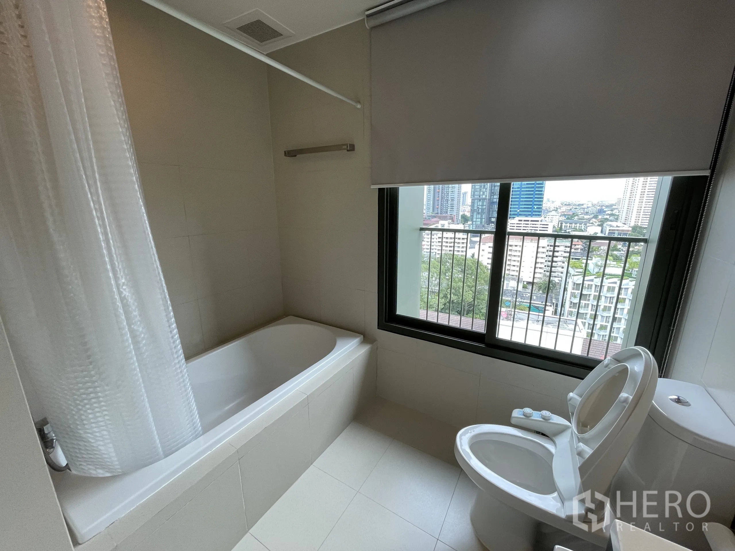 คอนโด ให้เช่าในWatthana, Bangkok - ห้องน้ำมีอ่างอาบน้ำและโถสุขภัณฑ์ข้างหน้าต่างที่มองเห็นวิวเมือง