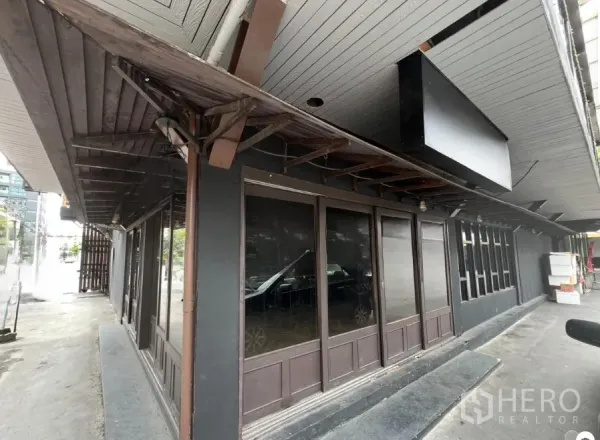 Retail Space for rent in Watthana, Bangkok - Ground-floor corner retail facade with dark wood awning and full-height glass windows in the Thonglor area.