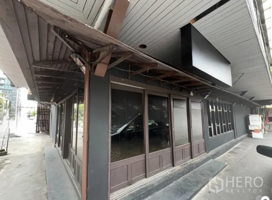 Retail Space for rent in Watthana, Bangkok - Ground-floor corner retail facade with dark wood awning and full-height glass windows in the Thonglor area.