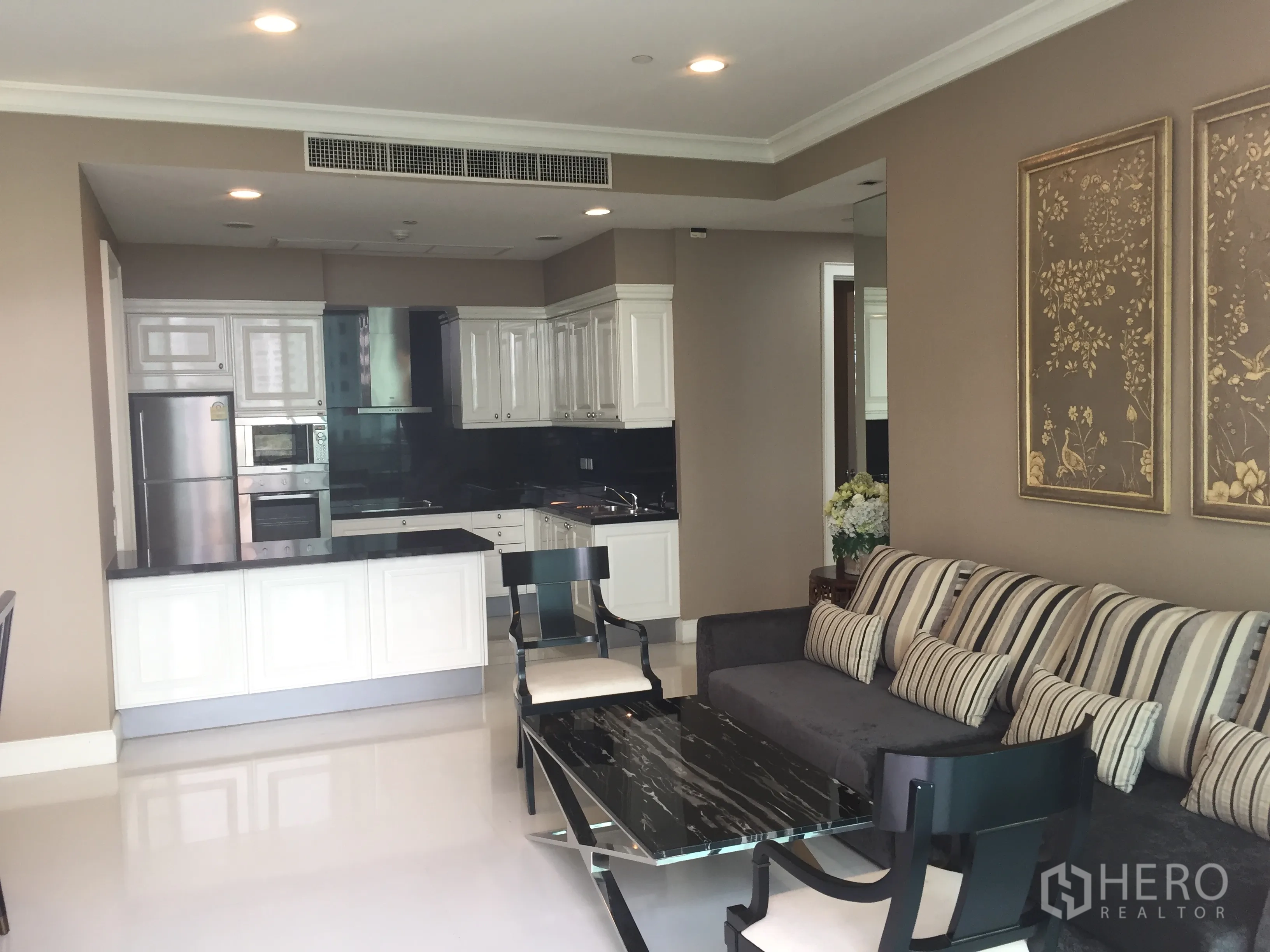 Condominium for rent in Watthana, Bangkok - Modern open kitchen with white cabinetry, black stone countertops and stainless appliances.