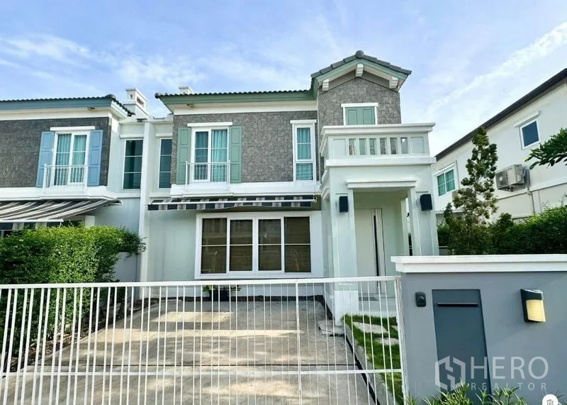 独立式住宅 出租或出售在Prawet, Bangkok - 现代两层独栋住宅正立面，带栅栏车位、小草坪与二层阳台（曼谷Prawet）。