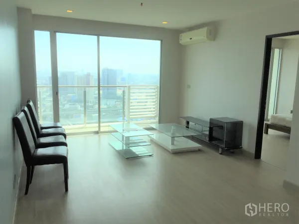 Condominium for sale in Watthana, Bangkok - Bright living room with floor-to-ceiling windows, balcony, and panoramic Bangkok skyline view.