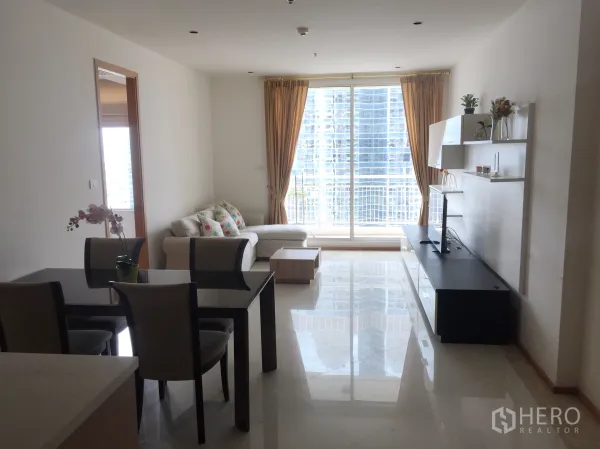 Condominium for rent in Sathon, Bangkok - Bright living and dining area with sofa, TV console and floor-to-ceiling windows overlooking the Bangkok skyline.