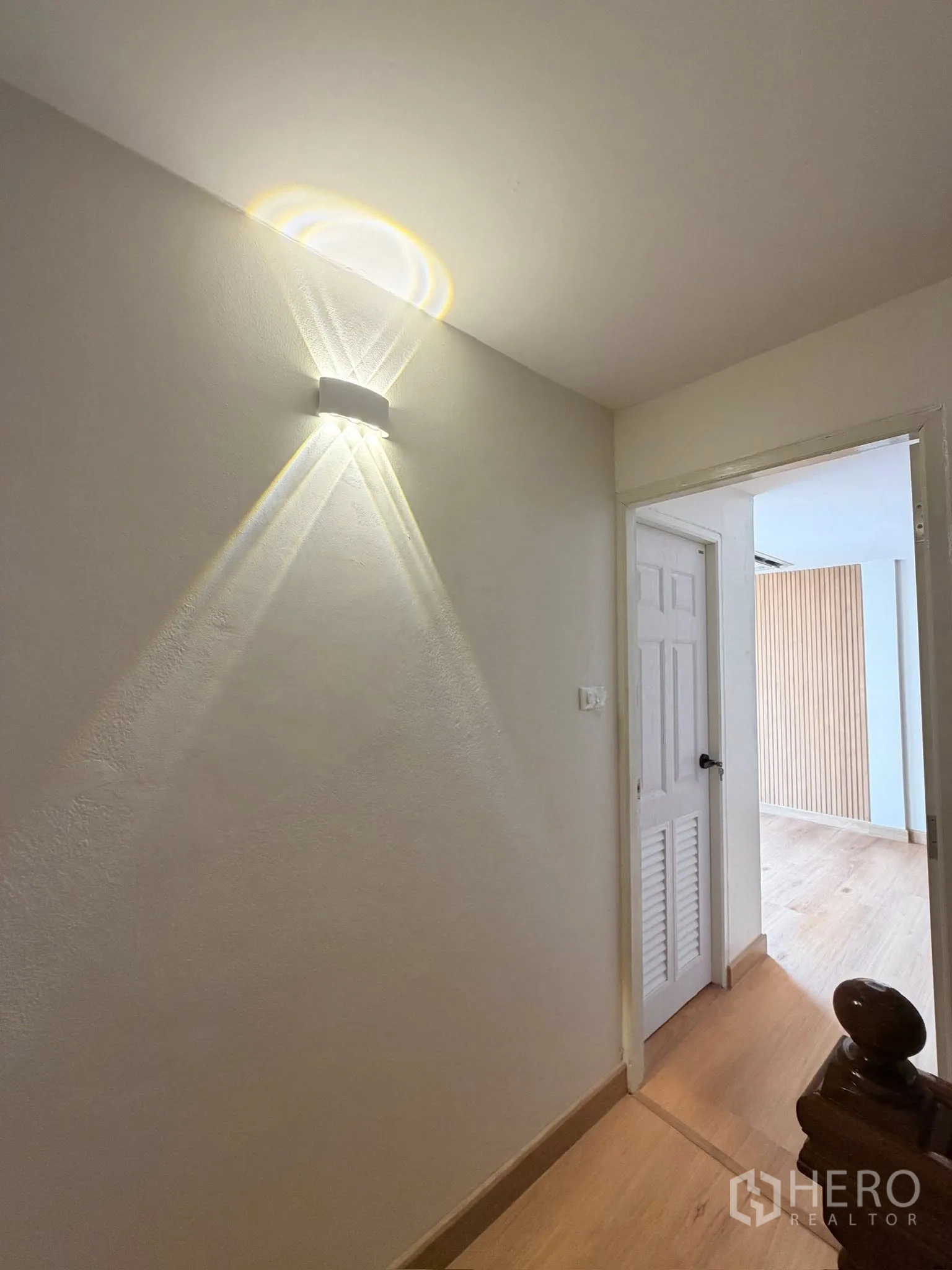 Townhouse for rent or sale in Yan Nawa, Bangkok - Upper hallway with decorative wall light leading to a bright room.