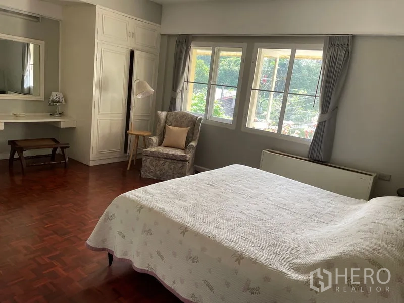 Condominium for rent in Watthana, Bangkok - Corner bedroom with bay-style windows, dressing table and armchair.
