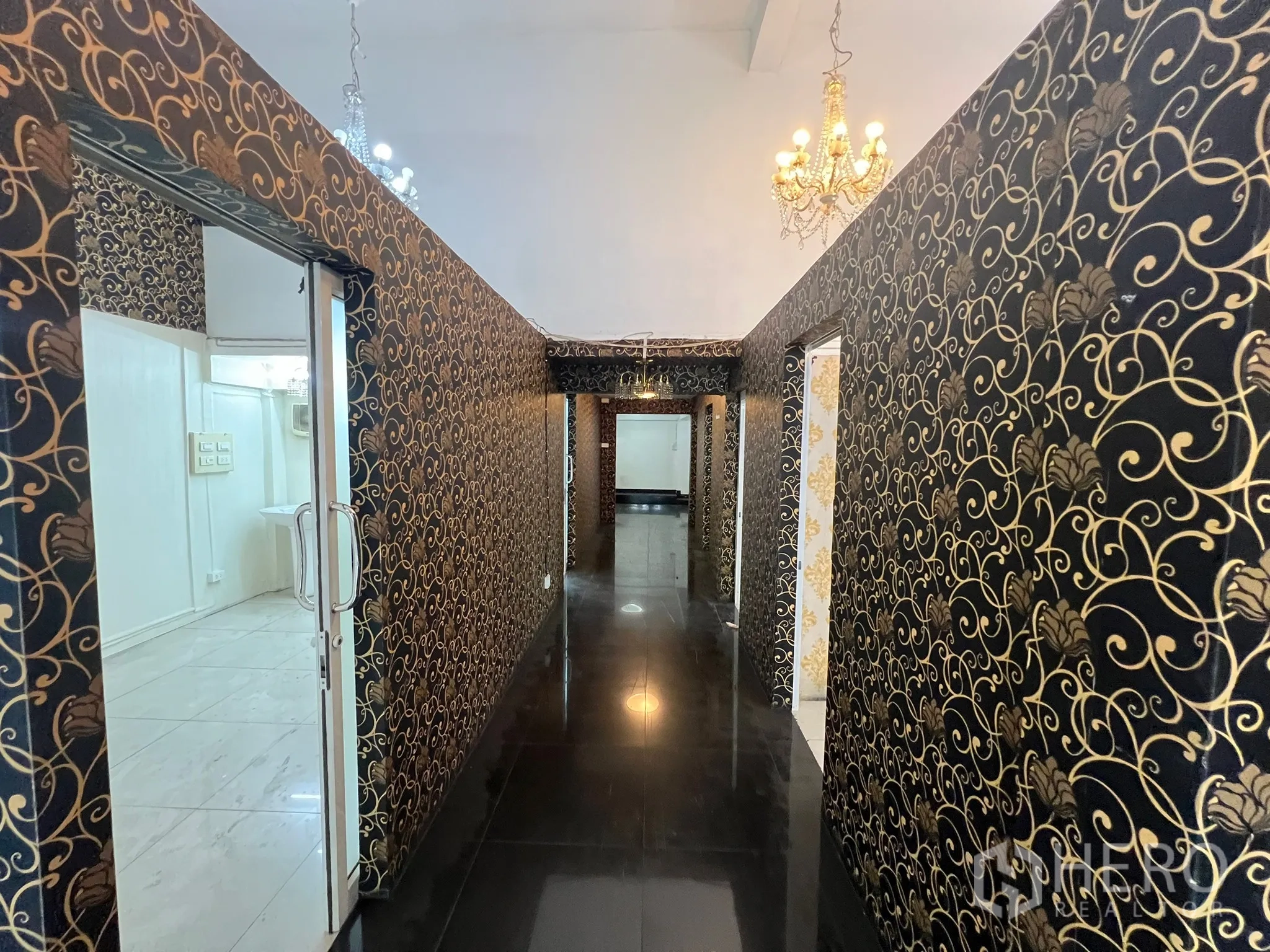 Shophouse for rent in Khlong Toei, Bangkok - Hallway lined with black-gold wallpaper and chandeliers leading to a rear room.