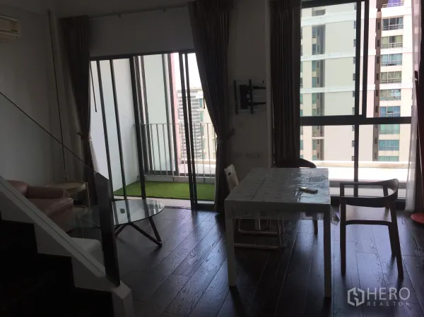 公寓 出租在Ratchathewi, Bangkok - 客餐厅连接带人造草坪的阳台，近帕亚泰轻轨站的城市景观。