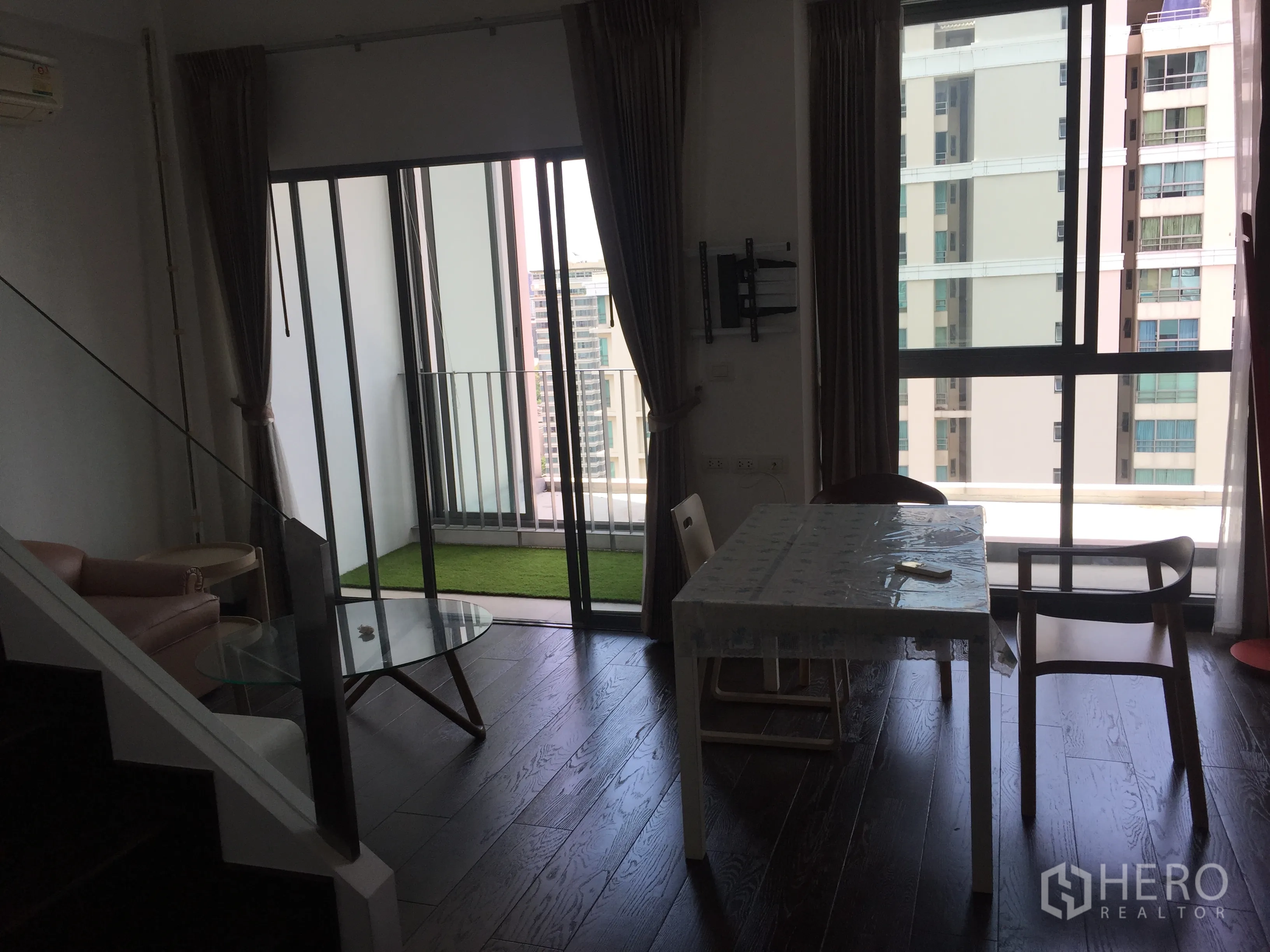 公寓 出租在Ratchathewi, Bangkok - 客餐厅连接带人造草坪的阳台，近帕亚泰轻轨站的城市景观。