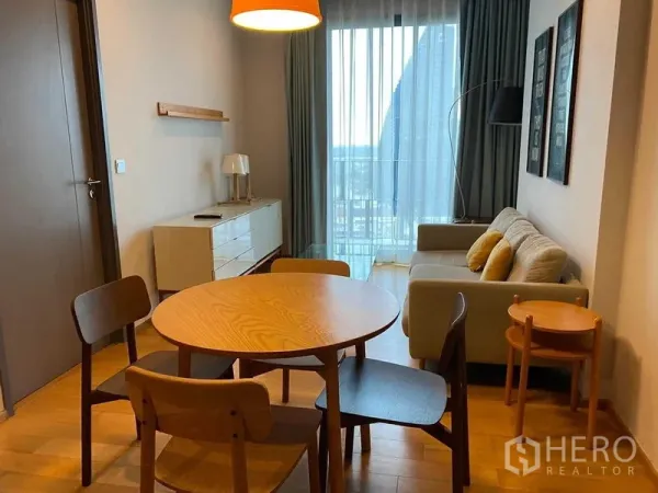 公寓 出租在Khlong Toei, Bangkok - 开放式客餐厅，圆形木餐桌、沙发与带纱帘的阳台落地窗。