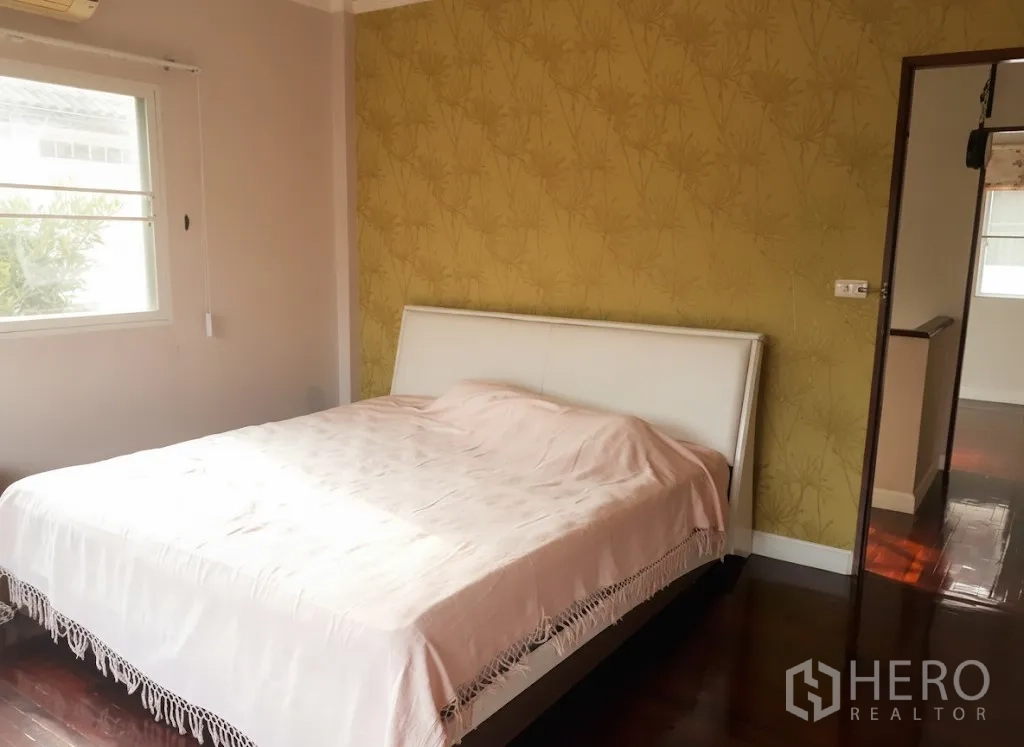 Detached House for rent in Lat Krabang, Bangkok - Master bedroom with yellow feature wall, large window and polished wood flooring.
