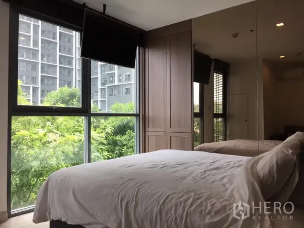 Condominium for rent in Phra Khanong, Bangkok - Bedroom with floor-to-ceiling windows, built-in wardrobe, mirrored wall, and green views.