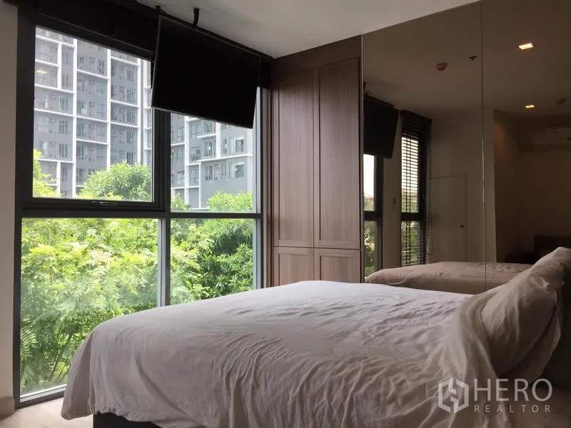 Condominium for rent in Phra Khanong, Bangkok - Bedroom with floor-to-ceiling windows, built-in wardrobe, mirrored wall, and green views.