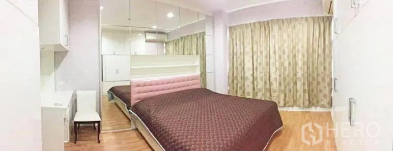 公寓 出租在Ratchathewi, Bangkok - 卧室配棕色绗缝床品、镜面墙、内置书桌与长窗帘。