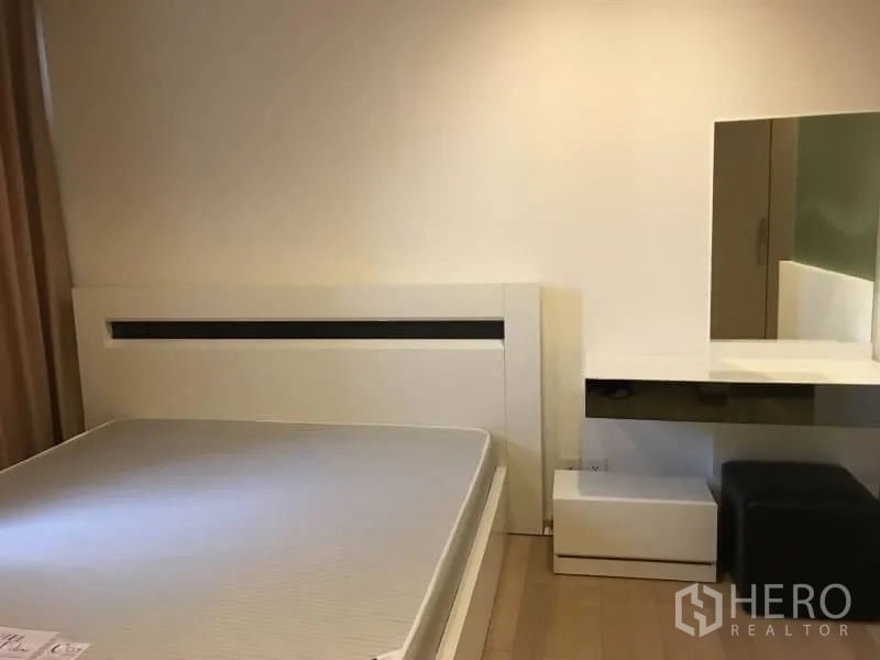 Condominium for rent in Khlong Toei, Bangkok - Minimalist bedroom with white bedframe, built-in dressing table, and light wood flooring.