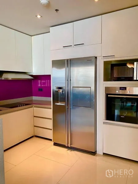 Condominium for rent - Modern L-shaped kitchen with white cabinetry, stainless fridge and built-in oven