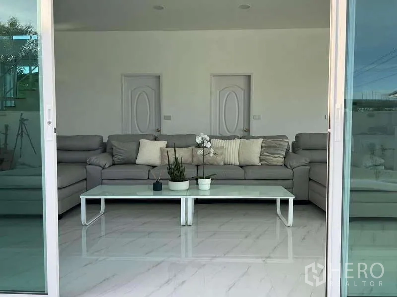 Detached House for rent in Lat Krabang, Bangkok - Sliding doors opening to a living room with a gray sofa and white coffee table.