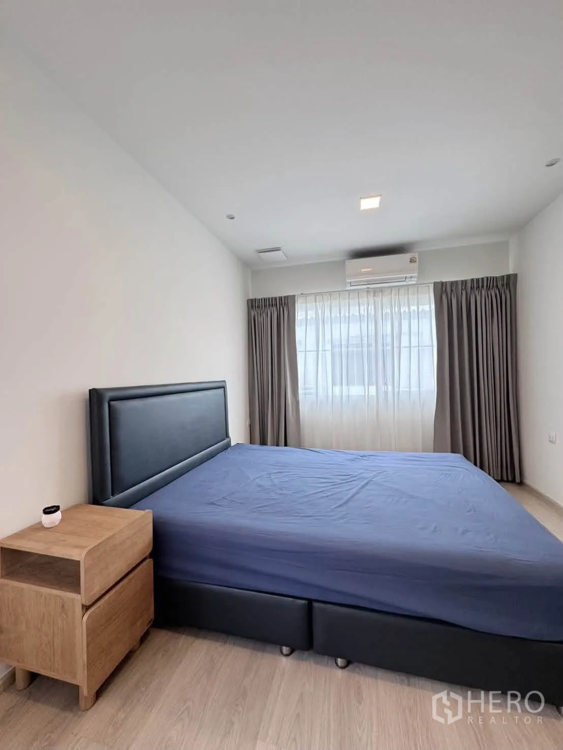 บ้านเดี่ยว for rent in Bang Phli, Samut Prakan - ห้องนอนเตียงหุ้มหนังสีเข้ม โต๊ะข้าง แอร์ และหน้าต่างติดผ้าม่าน