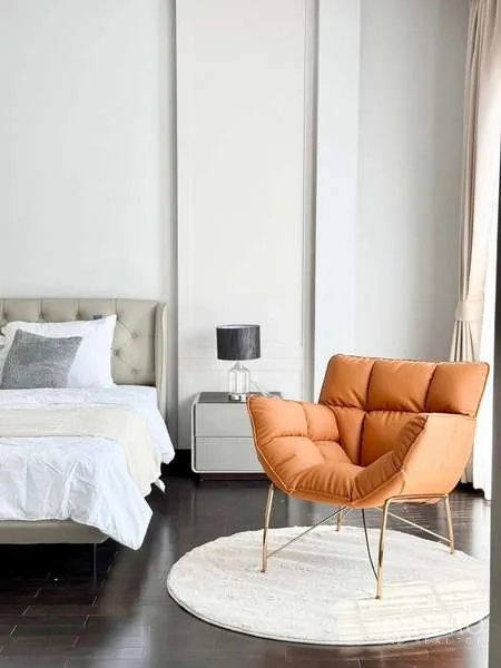 Detached House for rent or sale in Bang Phli, Samut Prakan - Cozy bedroom corner featuring an orange accent chair on a round rug next to the bed and nightstand.