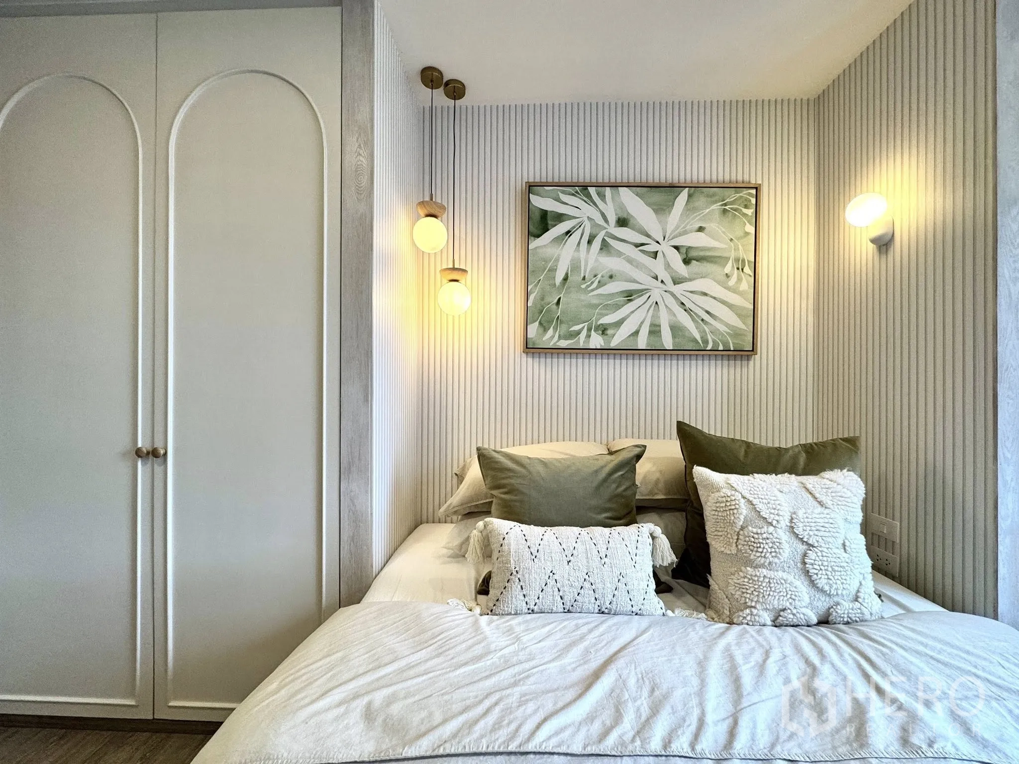 Condominium for rent in Watthana, Bangkok - Second bedroom with white paneled wardrobe, botanical artwork, and wall sconces.