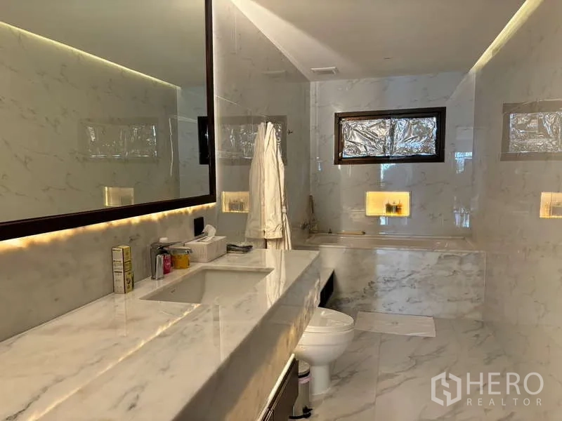Condominium for rent in Watthana, Bangkok - Marble bathroom featuring a bathtub, built-in niches and warm lighting.