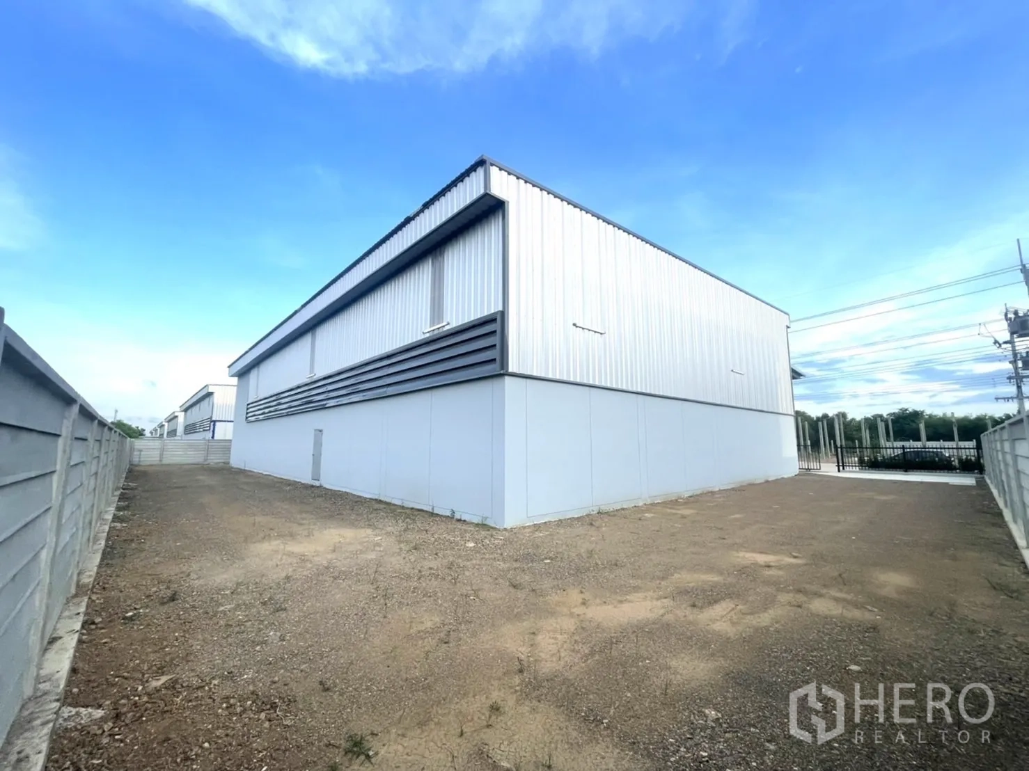 Factory for rent or sale in Bang Yai, Nonthaburi - Wide rear yard area with gravel surface and perimeter wall.