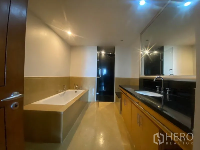 Condominium for rent in Sathon, Bangkok - Primary bathroom with bathtub, long twin vanity counter, and separate glass shower room.