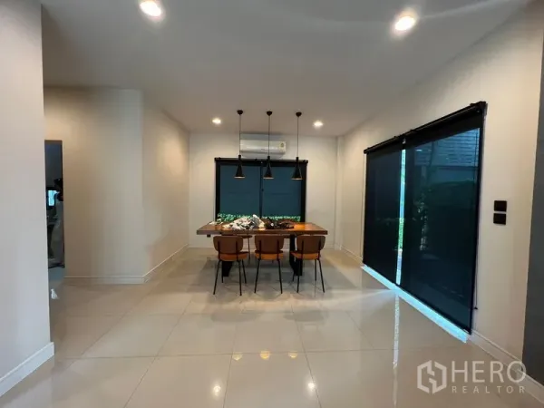 Detached House for rent or sale in Bang Kapi, Bangkok - Dining area with pendant lights, four chairs and sliding doors with dark blinds.