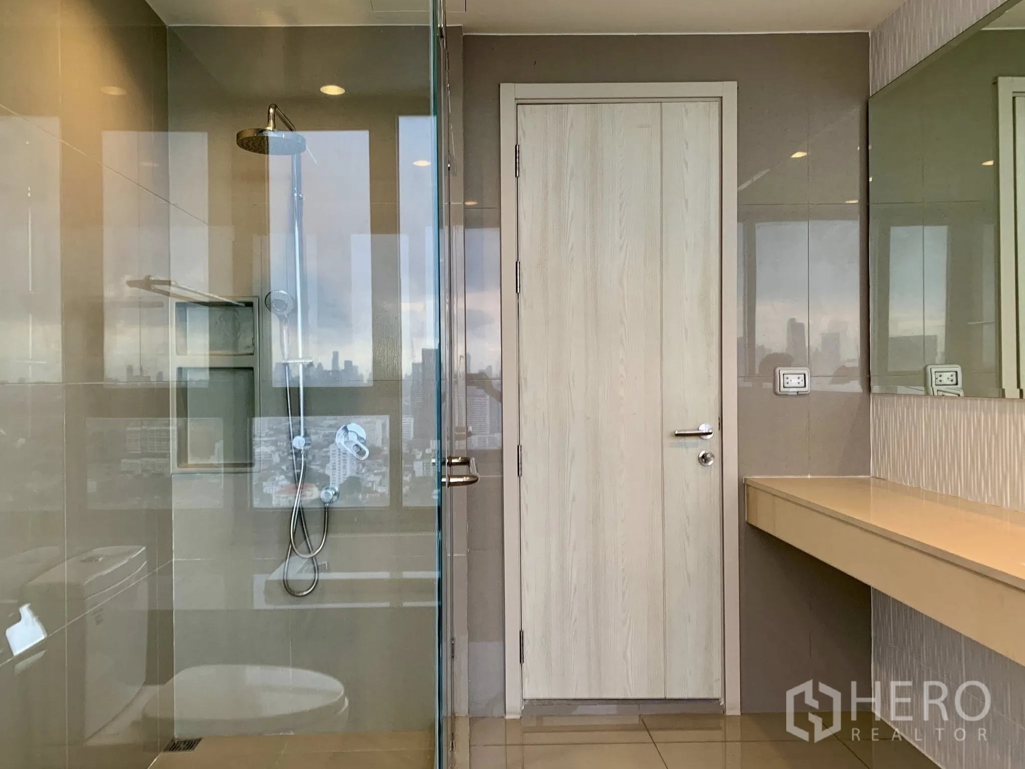 คอนโด for rent in Khlong Toei, Bangkok - ห้องน้ำสไตล์โมเดิร์นพร้อมห้องอาบน้ำกระจก เคาน์เตอร์ยาว และแสงสะท้อนเมืองบนกระจก