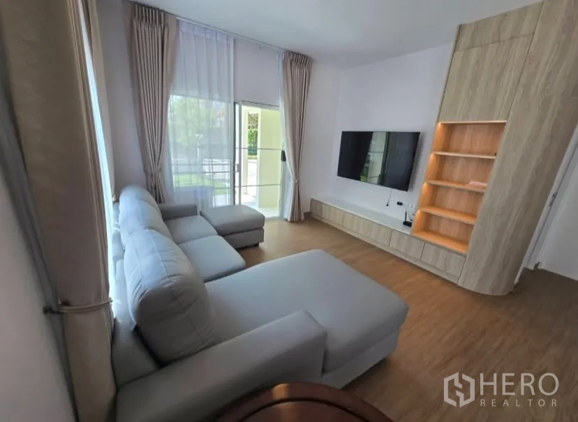 独立式住宅 for rent in Bang Phli, Samut Prakan - 明亮客厅，推拉玻璃门通向花园，设电视墙柜。