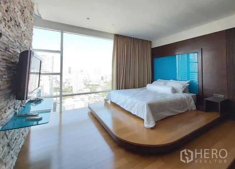 Condominium for rent in Watthana, Bangkok - Master bedroom on a raised platform with floor‑to‑ceiling windows and city view.