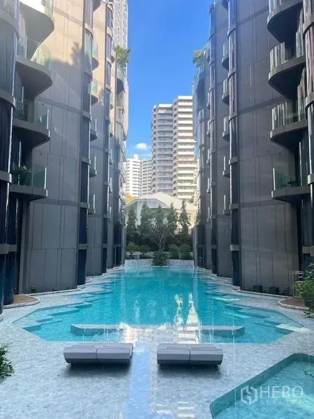公寓 出租在Watthana, Bangkok - 两栋楼之间的度假风泳池，配躺椅与清澈水面