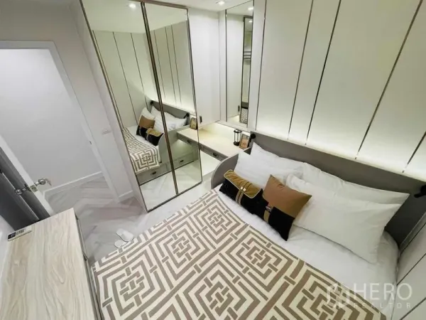 公寓 出售在Yan Nawa, Bangkok - 紧凑卧室，镜面衣柜、床头柜与几何图案床品。