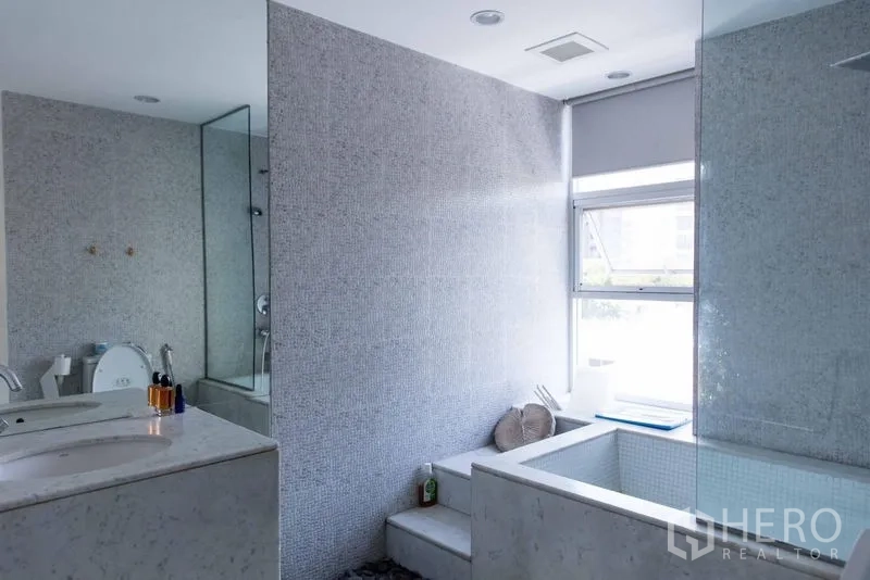 Townhouse for sale - Bathroom with mosaic tiles, sunken bathtub and a window bringing in natural light.