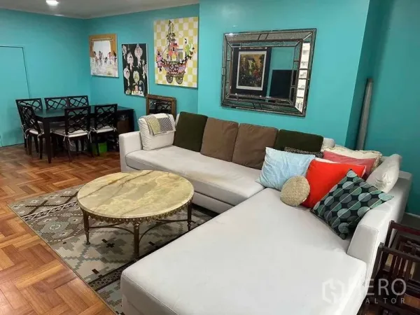 Condominium for sale in Bangkok - Open-plan living and dining area with sectional sofa, marble table and wall art.