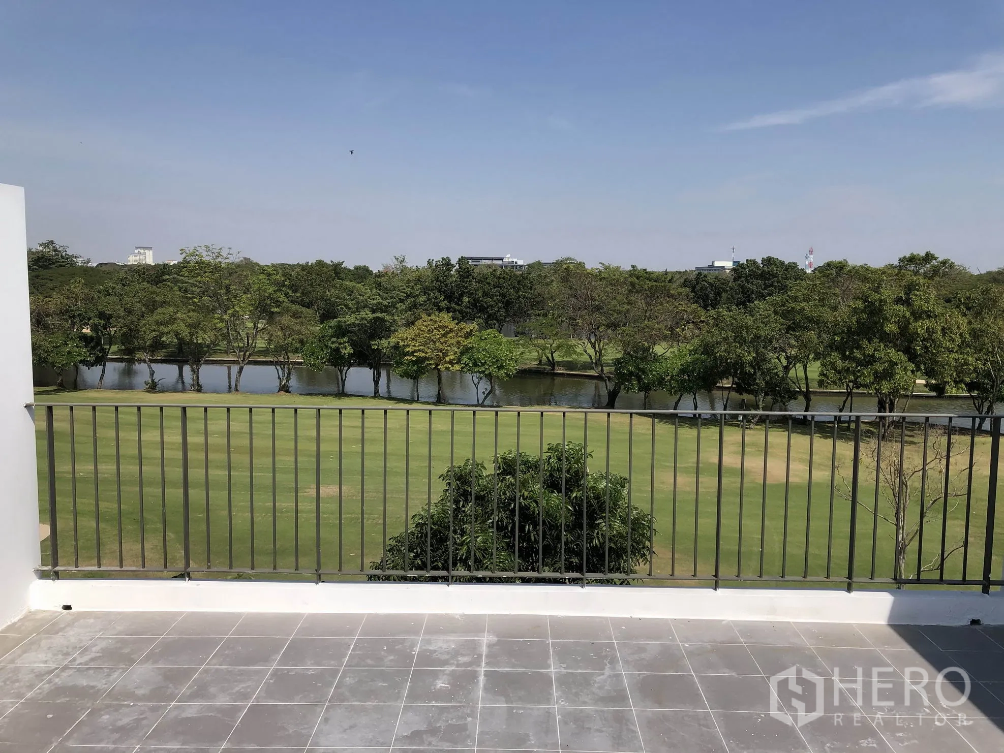 联排别墅 出租在Bang Kapi, Bangkok - 宽敞露台，金属栏杆外是草地与湖泊景观。