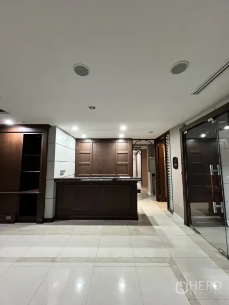 Office Space for rent in Watthana, Bangkok - Front-facing reception counter with wood cabinetry and spotlights.