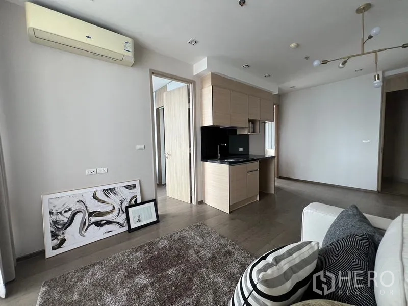 Condominium for sale - Living area corner with sofa, area rug, air conditioner and framed art on the floor.