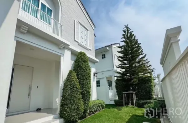 独立式住宅 出租在Bang Phli, Samut Prakan - 前院草坪与修剪整齐的绿篱及高大常青树。