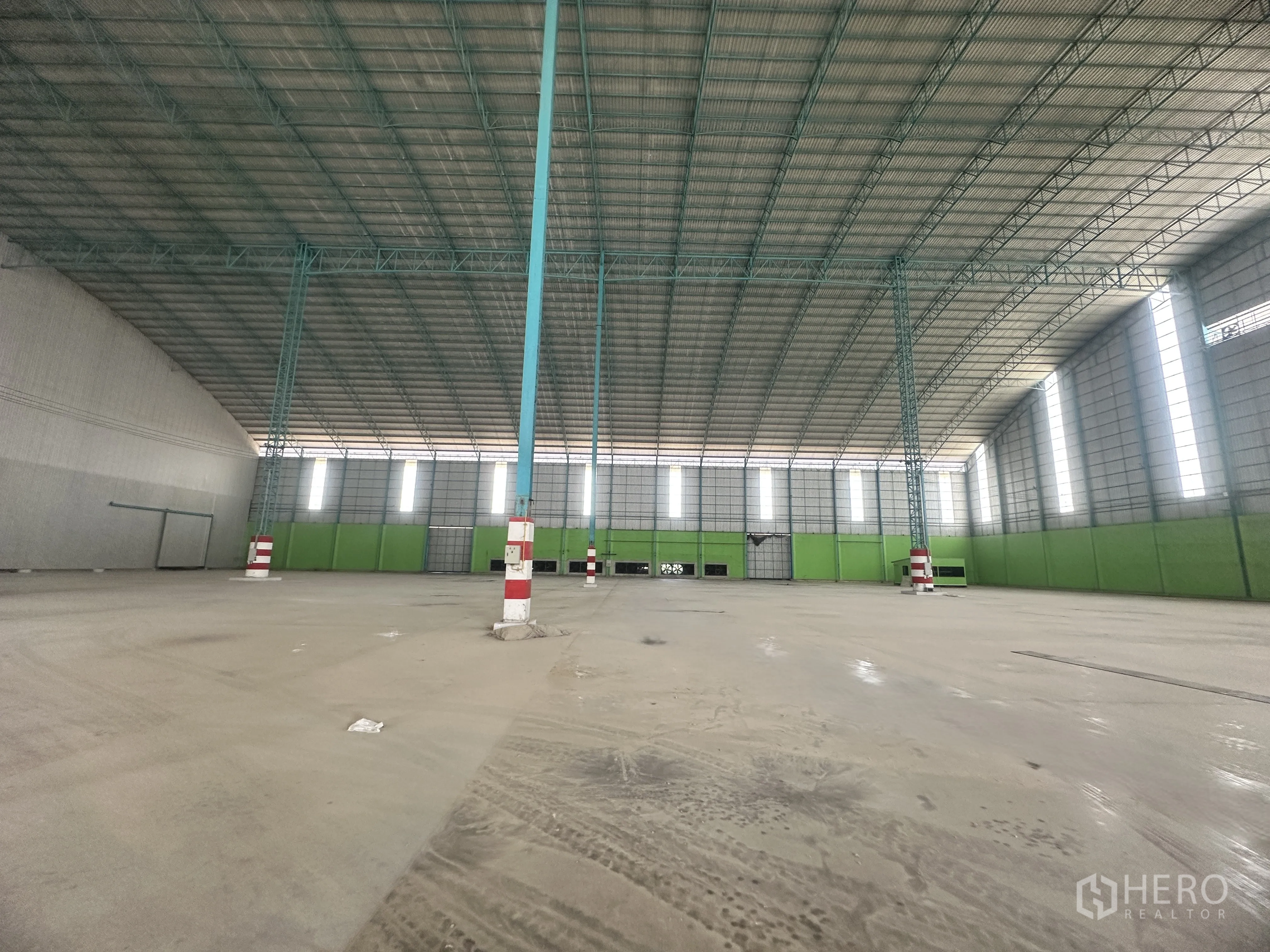 Warehouse for rent in Sai Noi, Nonthaburi - Open-plan warehouse floor showing evenly spaced columns, tall vertical windows, and wide access doors.