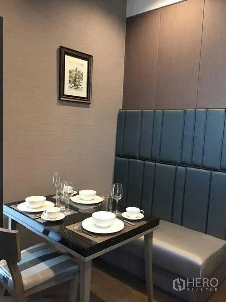 Condominium for rent in Bang Rak, Bangkok - Cozy dining nook with upholstered bench seating and a table set for four.