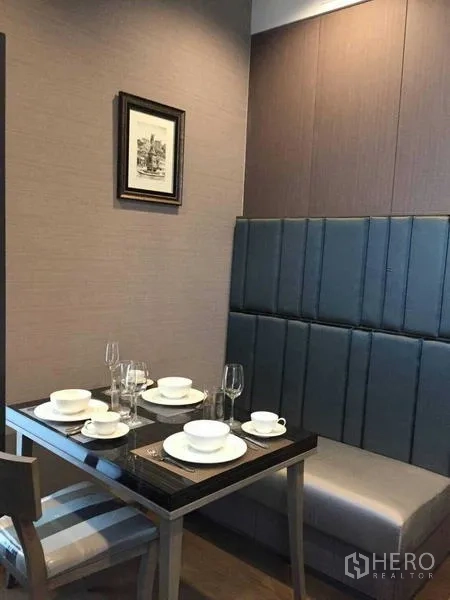 Condominium for rent in Bang Rak, Bangkok - Cozy dining nook with upholstered bench seating and a table set for four.