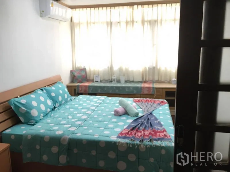 联排别墅 出租在Khlong Toei, Bangkok - 卧室配绿松石波点床品、窗边长凳、纱帘与空调。