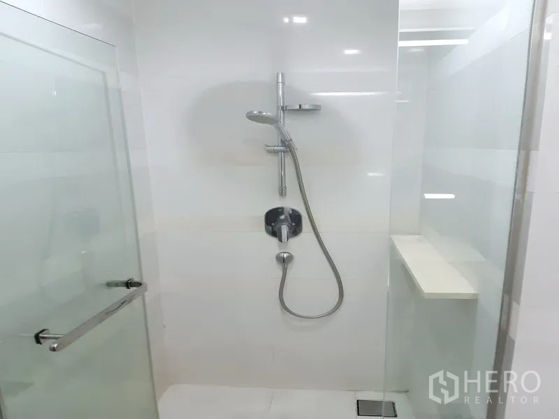 Condominium for rent in Khlong Toei, Bangkok - Glass-enclosed shower with handheld and rain shower fixtures.